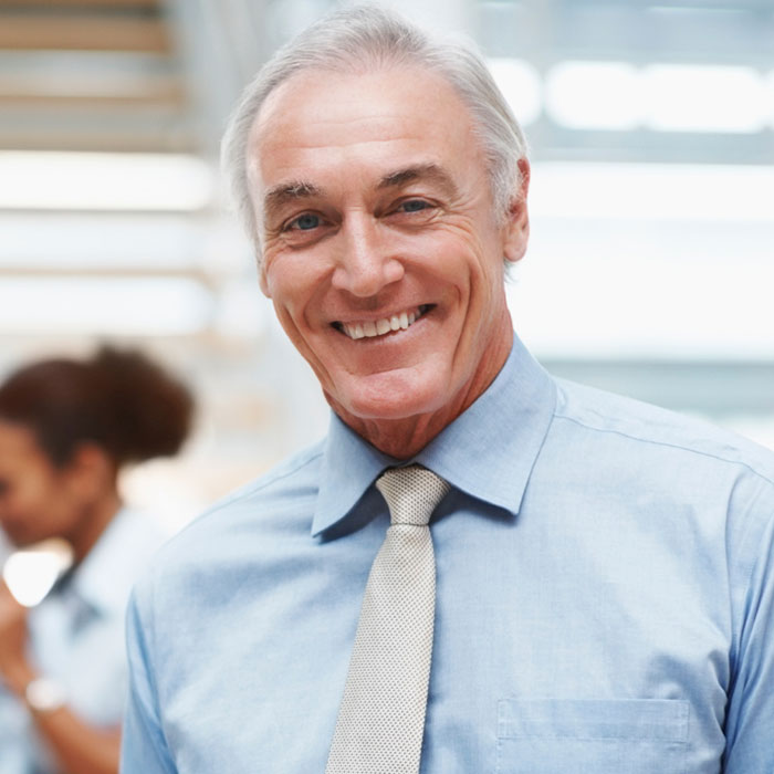 A man in a blue shirt and tie smiling.