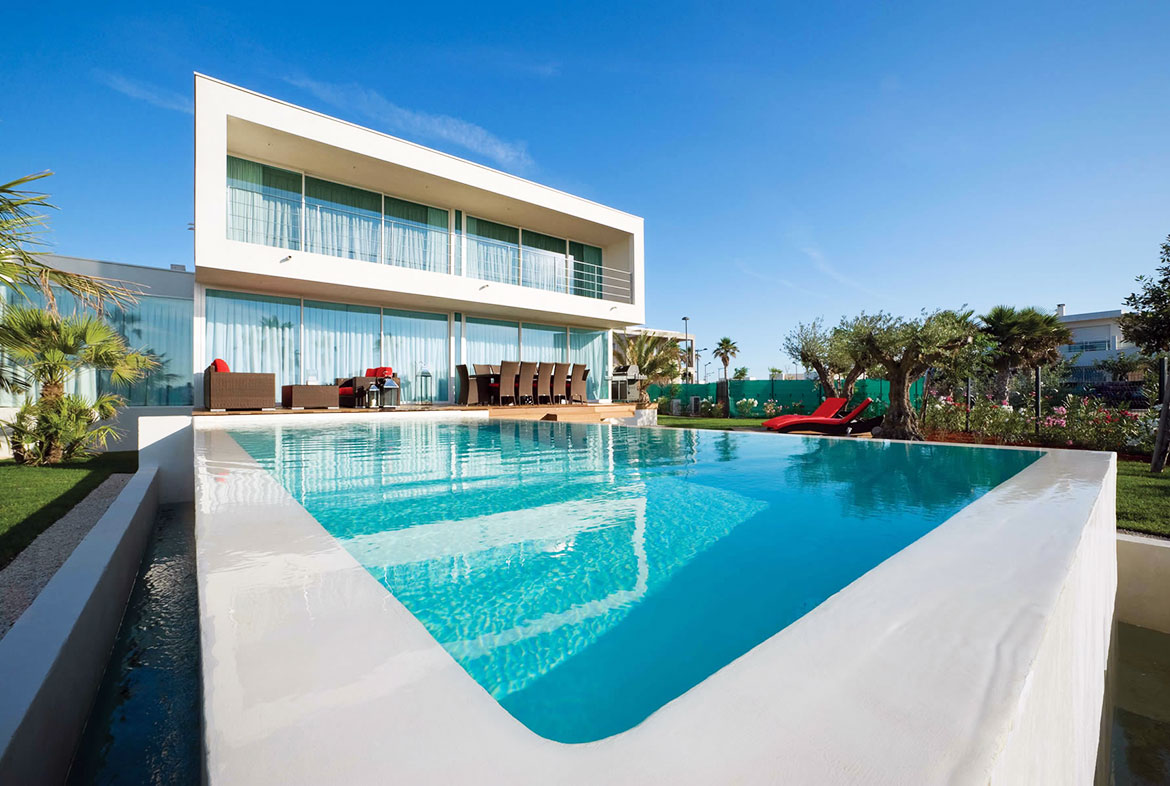 A large swimming pool with a house in the background.