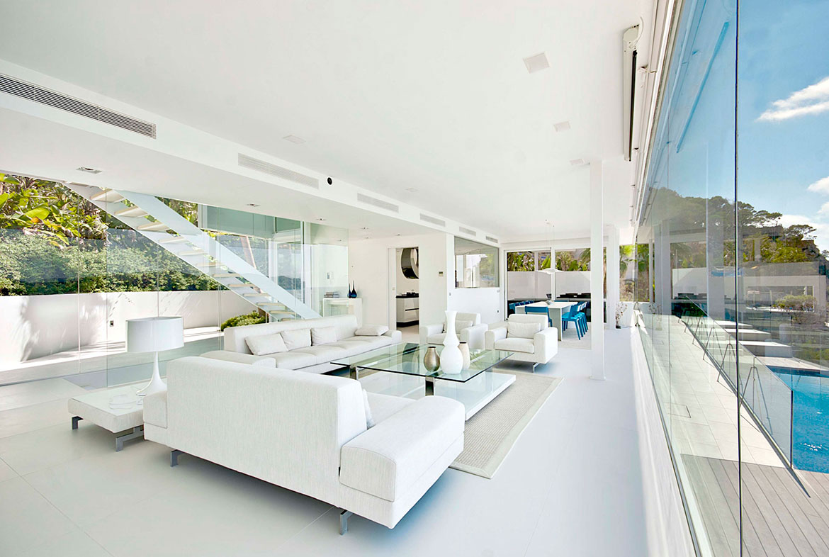 A living room with white furniture and a glass table.