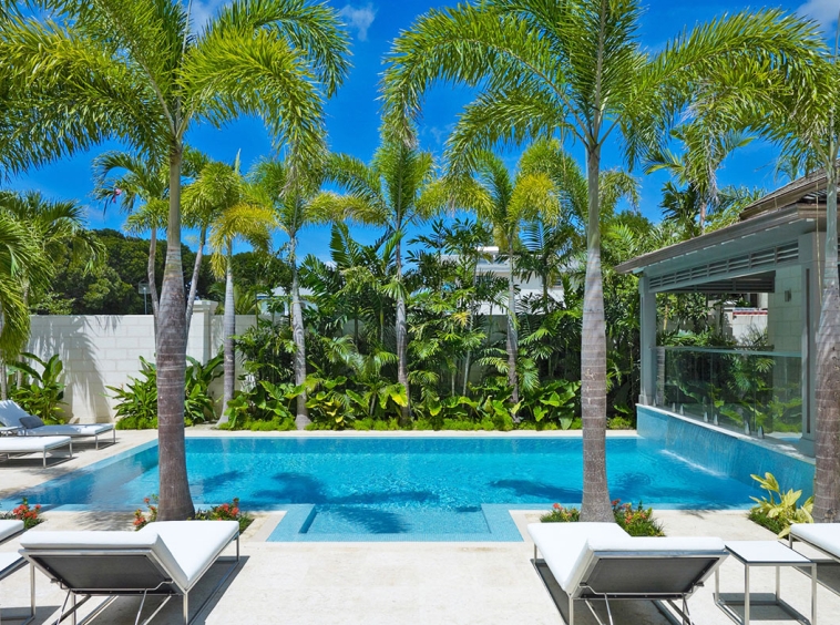 A pool with palm trees and chairs in the middle of it