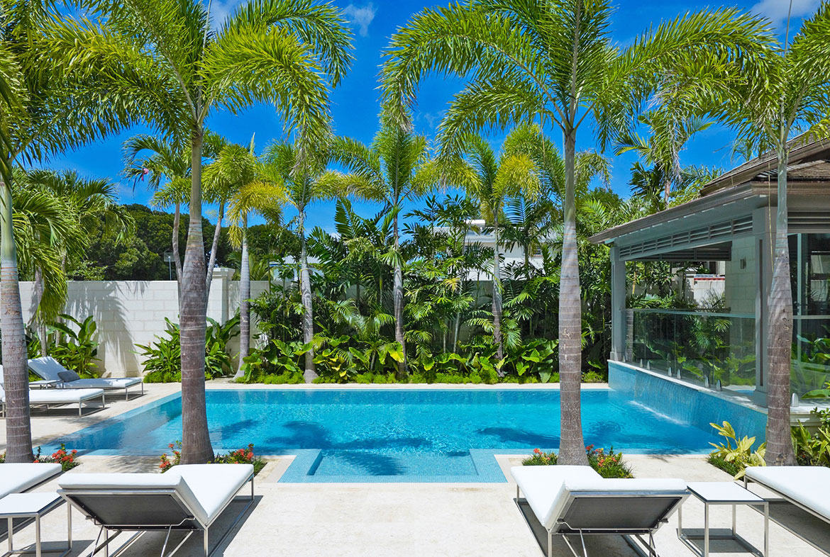 A pool with palm trees and chairs in the middle of it