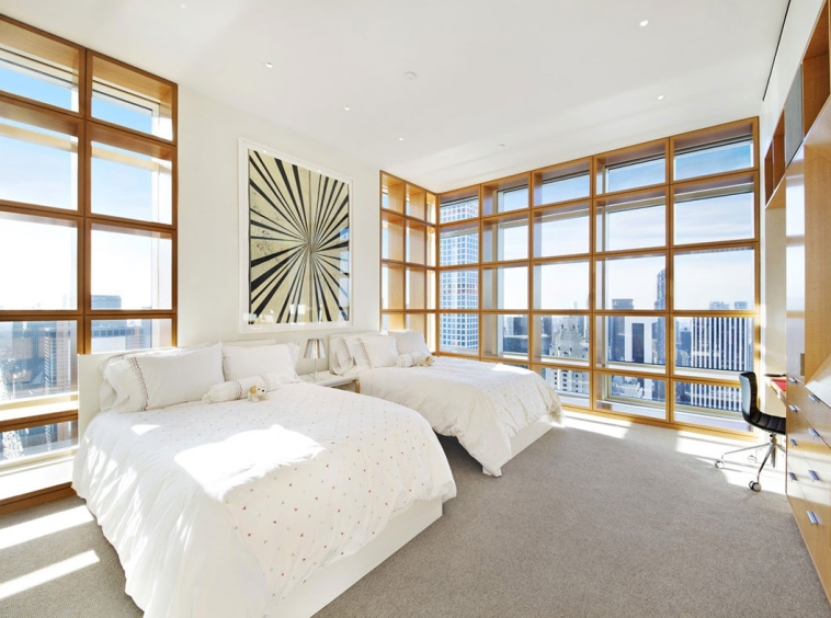 A bedroom with two beds and large windows.