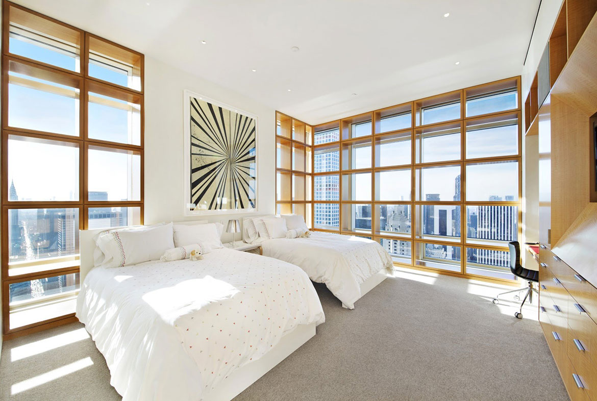 A bedroom with two beds and large windows.