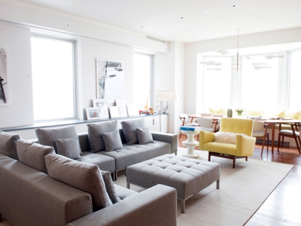 A living room with couches, chairs and ottomans.